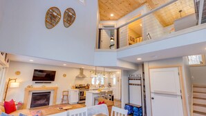 A spacious living area with a fireplace, dining table, and a kitchen in the background. - Waterville Estates- Tons of Amenities! (Campton)