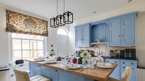 Una cocina con una isla central, armarios azules y una lámpara colgante.