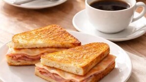 A sandwich on a plate with a cup of coffee beside it. - Motel Fascinação (Contagem)