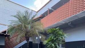 A courtyard with a stone planter, palm trees, and a white rabbit sculpture. - Motel Fascinação (Contagem)