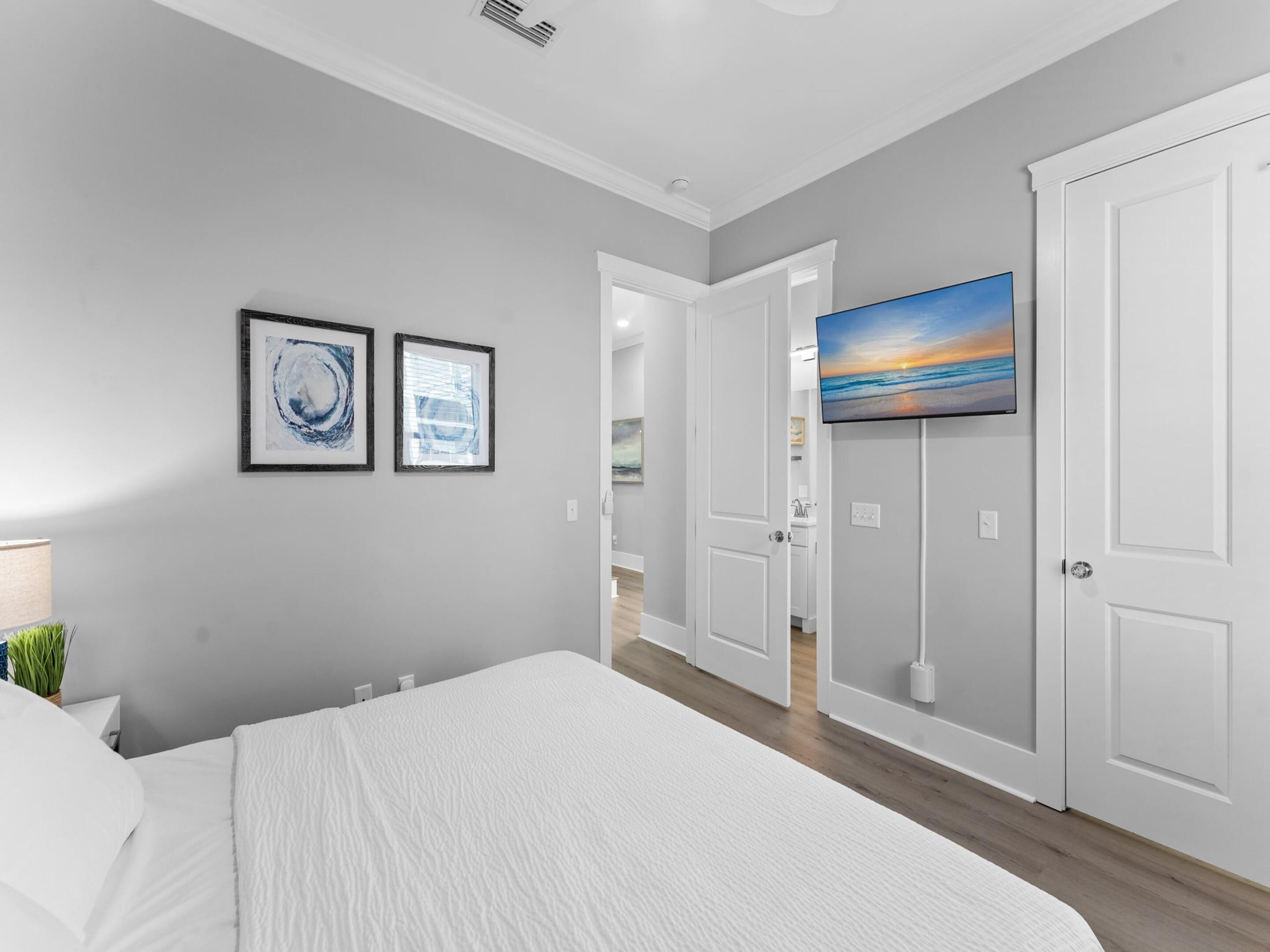 Un dormitorio con una cama grande, un televisor instalado en la pared y una puerta que da a un baño.