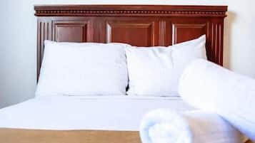 Un lit bien fait, avec des draps blancs et une serviette enroulée posée sur le lit.