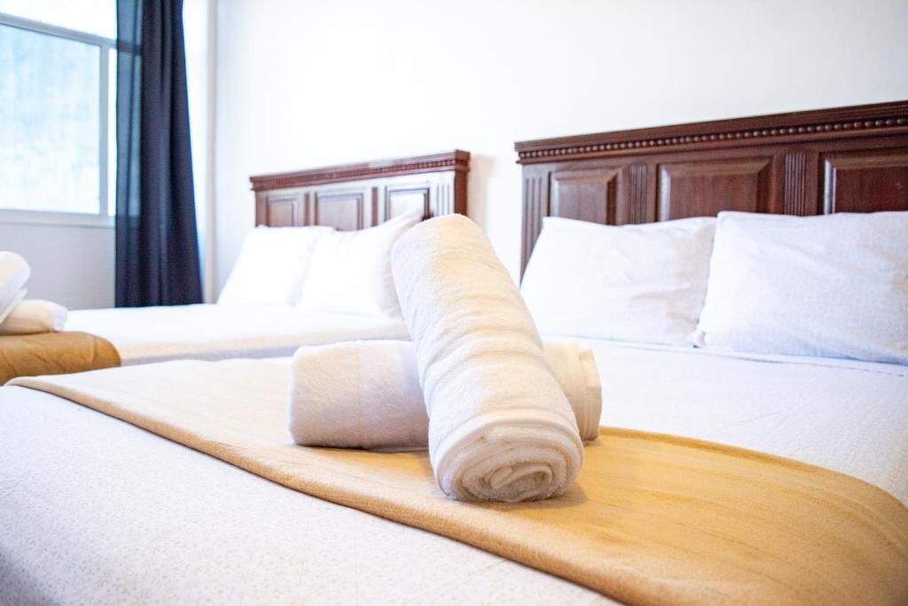 Una habitación de hotel con una cama bien hecha, un cabecero de madera y una ventana con cortinas.