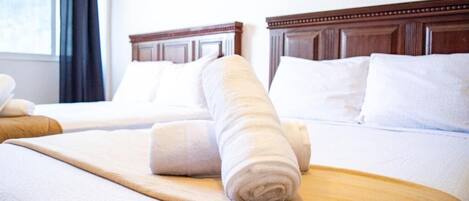 Una habitación de hotel con una cama bien hecha, un cabecero de madera y una ventana con cortinas.