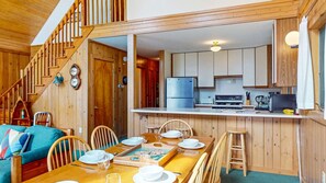 A wooden interior with a dining area, kitchen, and staircase.