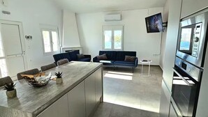 Una cocina moderna con una isla central, electrodomésticos integrados e iluminación colgante.
