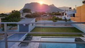 Terraza en la azotea con piscina, un pequeño jardín y vistas a una montaña al atardecer.