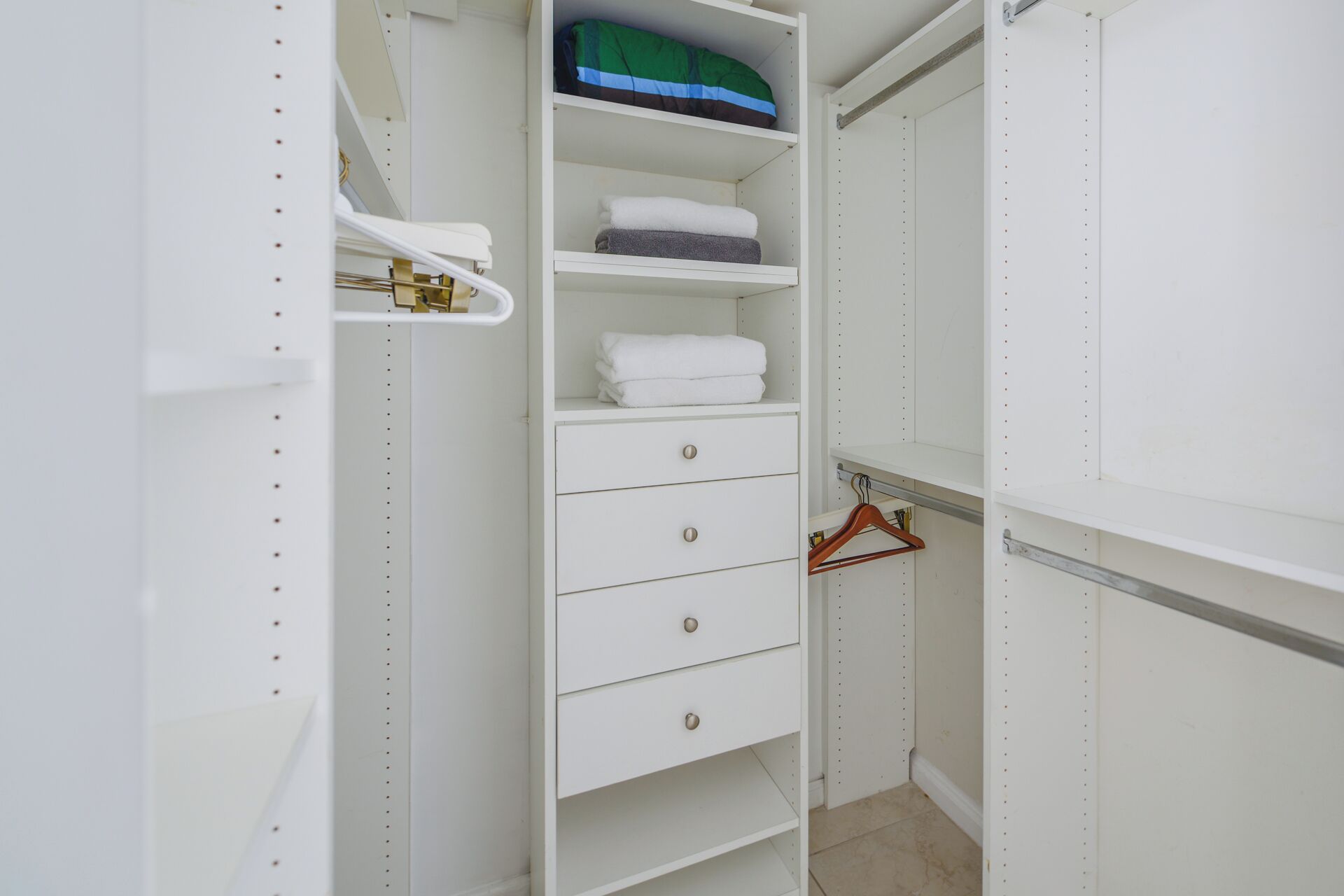 Een witte kast met planken, lades en een hanggedeelte.