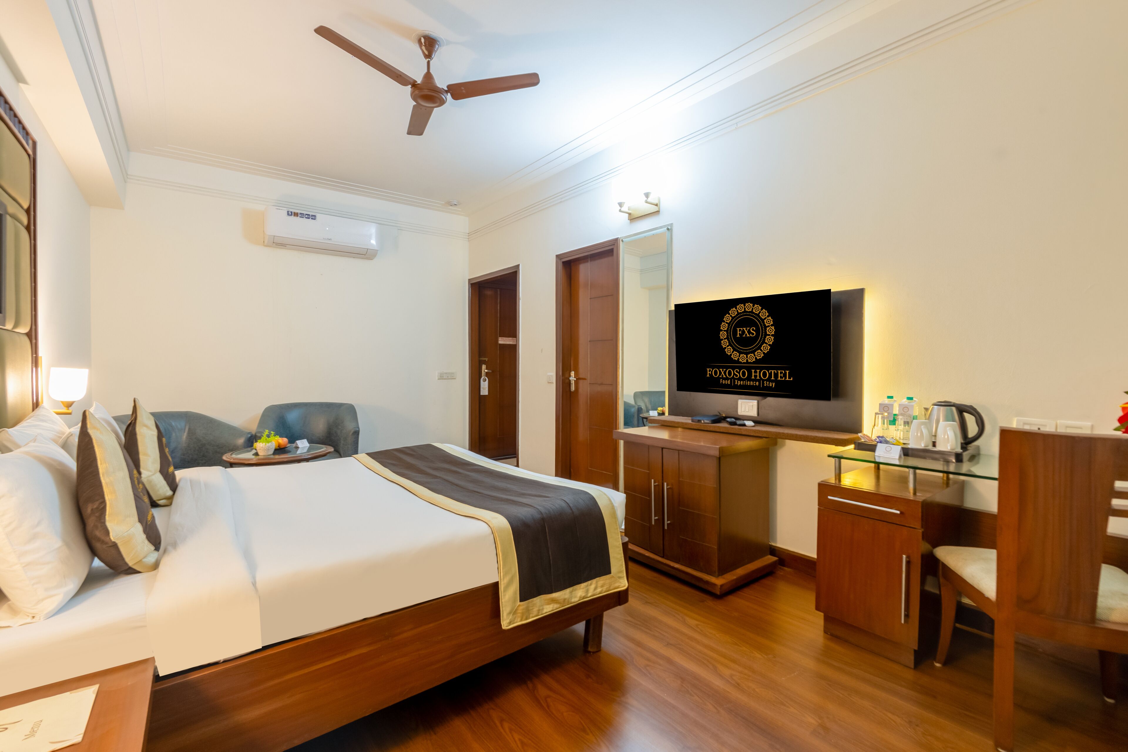 A hotel room with a bed, a desk, a television, and a wardrobe.
