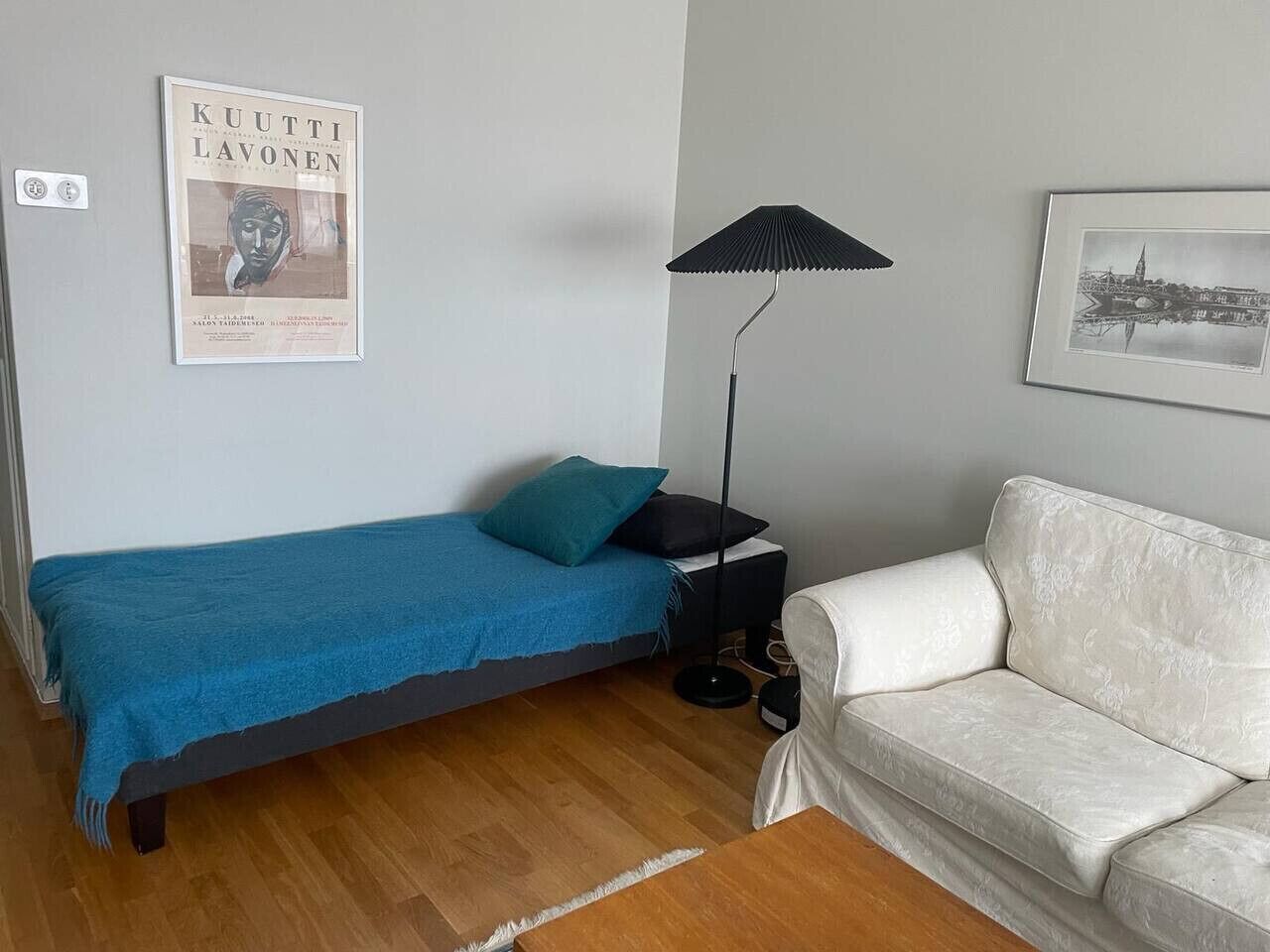 Une pièce comprenant un lit, une petite table avec une lampe, un canapé et un tableau encadré accroché au mur.