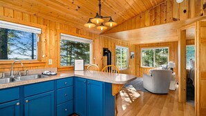 A wooden cabin interior with a kitchen featuring blue cabinets, a granite countertop, and a central island.