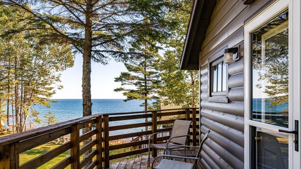 A wooden deck with a view of the ocean, a glass door, and a window.