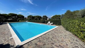 Una piscina rettangolare con bordatura in pietra, circondata da un patio in pietra.