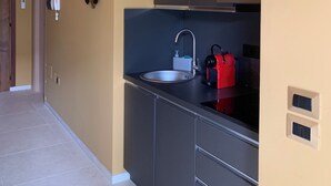 Una cucina moderna con lavello integrato, un bollitore rosso e un oggetto decorativo a parete.