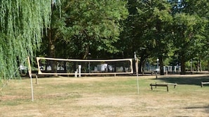 A volleyball net in a park with benches and trees. - ZEcamping 3 étoiles animé toboggans mobil-home 22m2 2 pers (Chateauroux)