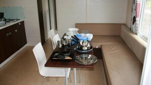 A compact kitchenette with a gas stove, a small fridge, and a dining table with chairs. - ZEcamping 3 étoiles toboggans dog friendly animations mobil-home TV (Chateauroux)