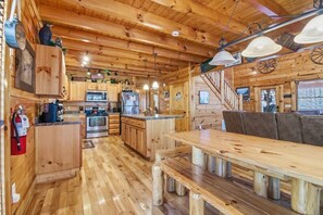 L’intérieur d’un chalet en bois comprend une cuisine, un coin repas et un escalier.