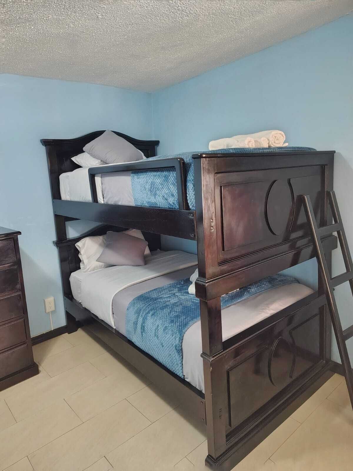 Una cama litera con dos niveles, un cabecero de madera y una escalera.