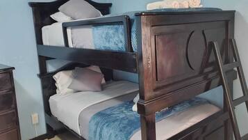 Una cama litera con dos niveles, un cabecero de madera y una escalera.