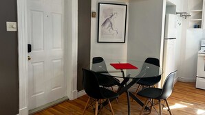 En matplats med ett glasbord, svarta stolar, en röd servett och ett inramat konstverk på väggen.