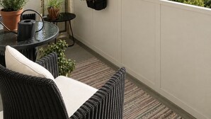 A balcony with wicker furniture, potted plants, and a hanging planter. - Borg Katariinankulma | Design Apt · Balcony With View · Free Parking (Pori)