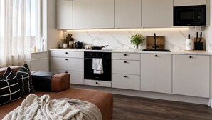 A modern kitchen with a built-in oven, microwave, and a marble countertop. - Borg Katariinankulma | Design Apt · Balcony With View · Free Parking (Pori)