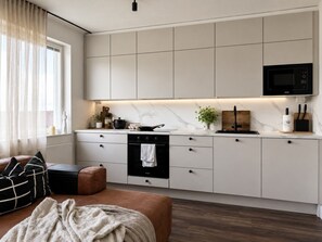 A modern kitchen with a built-in oven, microwave, and a marble countertop.