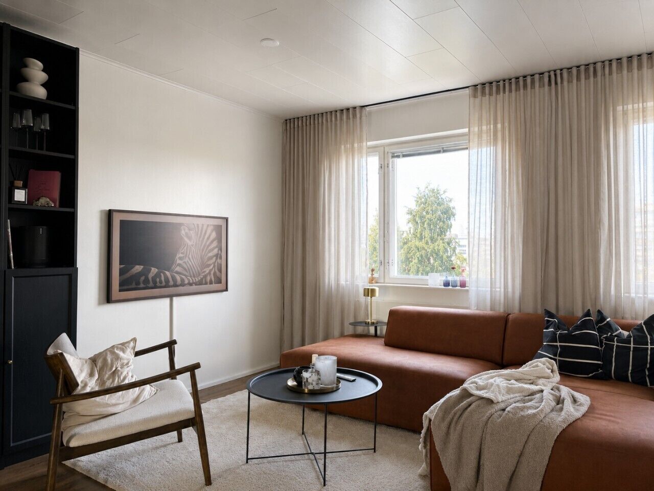 A modern living room with a sofa, a chair, a small round table, and a bookshelf.