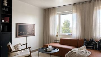 A modern living room with a sofa, a chair, a small round table, and a bookshelf.