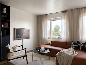 A modern living room with a sofa, a chair, a small round table, and a bookshelf.