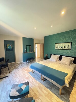 Une chambre à coucher avec un lit, un bureau, une chaise et un tableau accroché au mur.