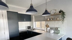 A modern kitchen with a central island, pendant lights, a microwave, toaster, and coffee maker.