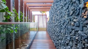 A corridor with a glass railing, a stone wall, and a wooden floor. - Beachfront Gourmet Studio with Private Pool (João Pessoa)