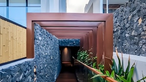 A modern interior corridor with a stone wall, wooden slats, and a glass railing. - Beachfront Gourmet Studio with Private Pool (João Pessoa)
