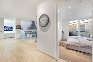 A modern hotel interior with a large wall clock, a kitchen area, and a seating area with a stone wall view. - Luxury bungalow with heated private pool, sauna & discreet and central location. (Düsseldorf)