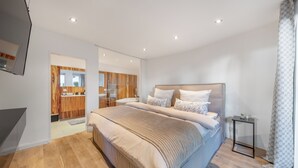 Un dormitorio moderno con una cama grande, suelo de madera y una mesita de noche pequeña.