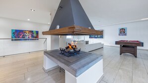 Un espacio interior moderno con chimenea de concreto, mesa de billar y obras de arte en las paredes.