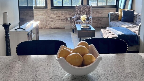 Un salón con una mesa de comedor, sillas, un sofá y un ventanal con persianas.