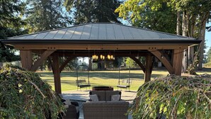 A covered outdoor seating area with a central fire pit, surrounded by stone pathways and small trees. - Peaceful-Cozy Home!
Modern Touches & Outdoor
Space! (Buckley)