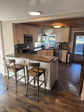 A modern kitchen with a central island, wooden chairs, and a view of the outdoors. - Peaceful-Cozy Home!
Modern Touches & Outdoor
Space! (Buckley)