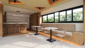 Une cuisine moderne agrémentée d’éléments en bois, un coin bar et un espace détente avec des tables et des chaises rondes.