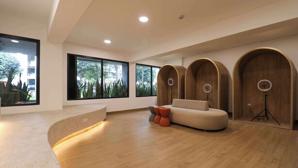 Un intérieur moderne avec un comptoir d’accueil incurvé, un canapé rond et un mur décoratif en bois intégrant des haut-parleurs.
