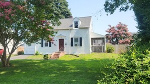 A single-story house with a front porch, a small front yard, and a tree with pink flowers. - Cozy 1-bedroom house in perfect Historical New Castle (New Castle)