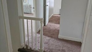 A hallway with carpeted stairs leading to a room with white walls and a door. - Cozy 1-bedroom house in perfect Historical New Castle (New Castle)
