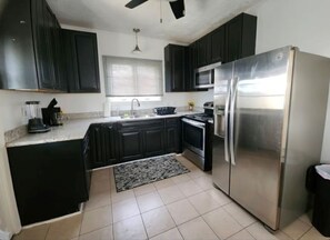 A modern kitchen with dark cabinets, stainless steel appliances, and a tiled floor. - Cozy 1-bedroom house in perfect Historical New Castle (New Castle)
