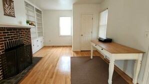 A spacious room with hardwood flooring, a fireplace, a white table, and a door leading to another room. - Cozy 1-bedroom house in perfect Historical New Castle (New Castle)