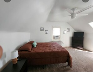 A bedroom with a bed, a nightstand, a lamp, a dresser, a ceiling fan, and a window. - Cozy 1-bedroom house in perfect Historical New Castle (New Castle)