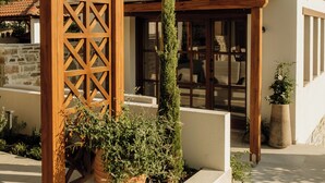 A building with a tiled roof, a wooden pergola, and a potted plant.
