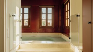 A room with a glass-enclosed hot tub, a window with a view of the outside, and a wooden door.