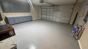 Eine Garage mit Betonboden, Deckenventilator und Rolltor.